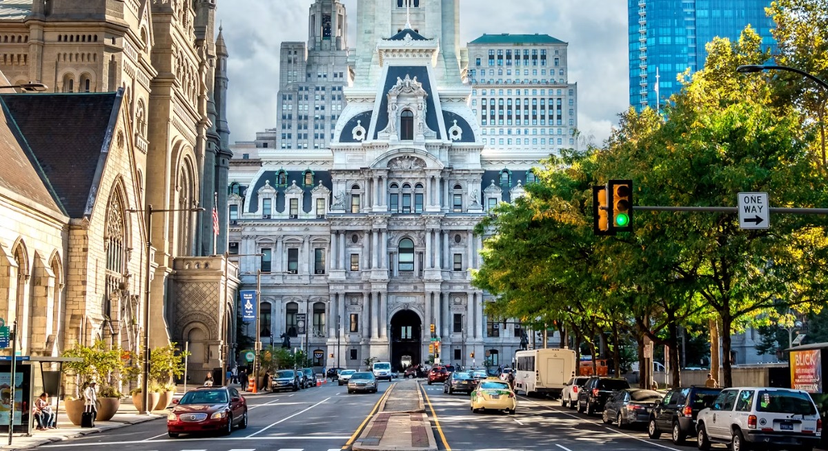 Philadelphia City Hall tower rising above a street with cars and a crosswalk